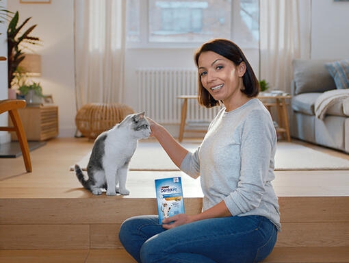 Lady sat with her cat holding Dentalife cat sticks